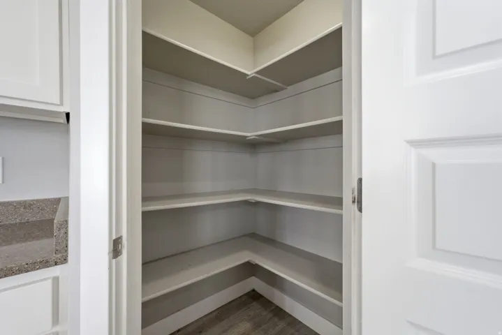 Corner pantry with multiple built-in shelves and wood-finish flooring
