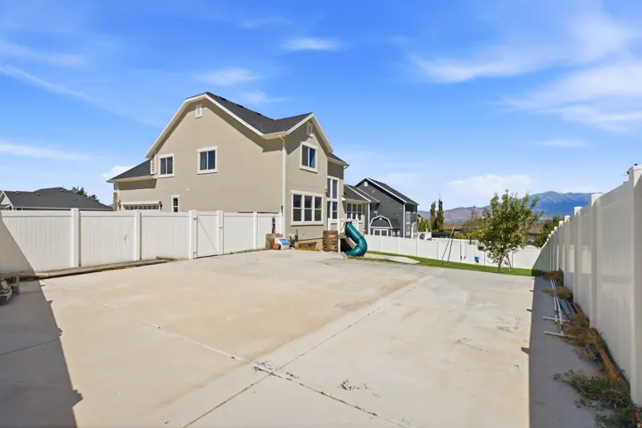 Expansive concrete pad with surrounding white fencing, grass area, and mountain backdrop