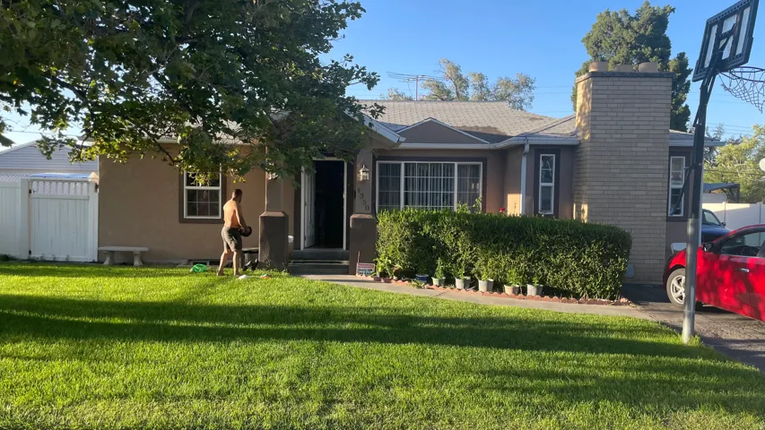 Stucco exterior featuring a prominent brick chimney, pitched roofline, and front porch