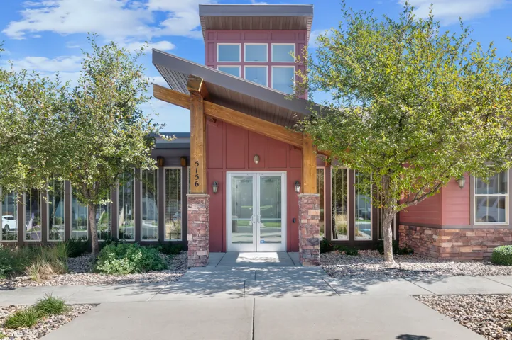 Modern facade featuring red siding, stone pillars, a prominent entryway, and extensive glazing