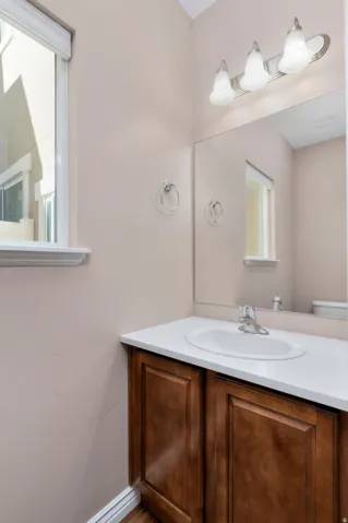 Built-in vanity with wood-finish cabinetry, white countertop, and an undermount sink