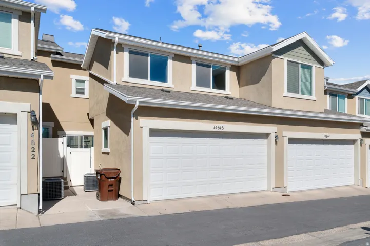 Neutral-toned exterior with multiple windows, two attached garages, and a light-colored roof