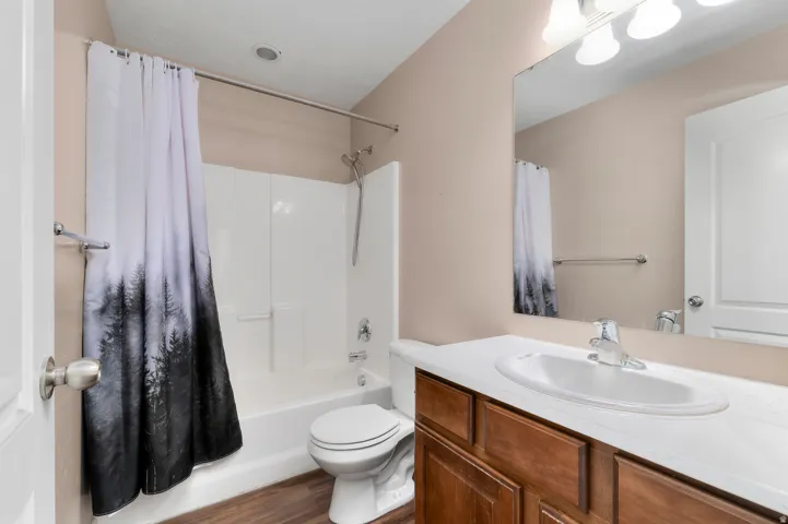Bathroom with a full bathtub/shower combination, wood-finish flooring, and a vanity with a built-in sink