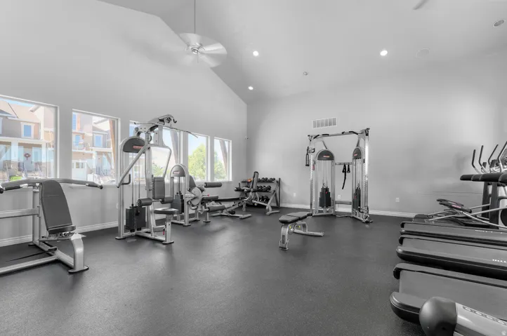 Fitness facility with vaulted ceilings, recessed lighting, ceiling fan, and multiple windows