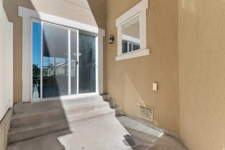 Rear patio area featuring a sliding glass door, a single window, and exterior lighting