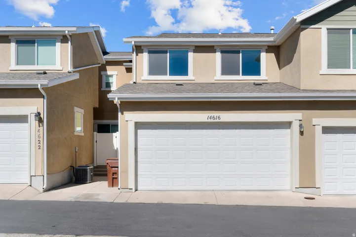 Tan stucco exterior with white trim windows and garage doors