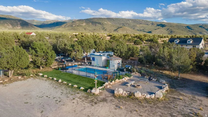 Outdoor pool, gravel fire pit area with stone seating, artificial turf, and extensive natural landscaping