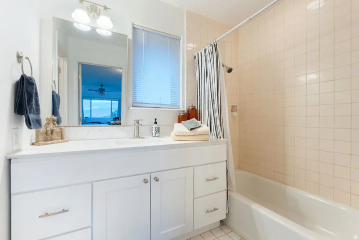 White vanity with integrated rectangular sink, stone-finish countertop, and brushed nickel faucet