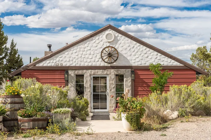 Gable roofline featuring textured white siding and a decorative wagon wheel accent