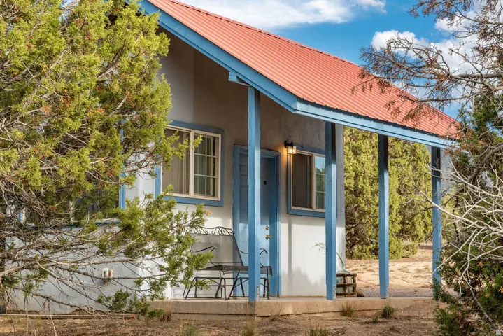 Exterior featuring a metal roof, stucco siding, and a covered front porch with support columns