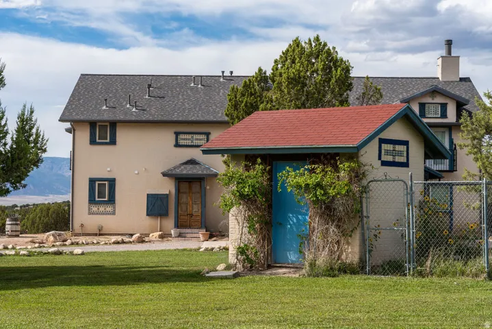 Stucco exterior with blue trim accents, asphalt shingle roofing, and a detached auxiliary structure with a red roof
