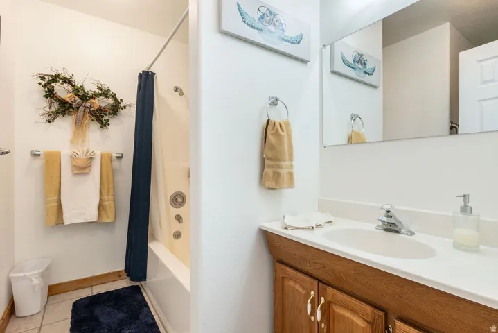Full bathroom featuring a single vanity, integrated sink, chrome faucet, and a tub/shower combination with a curtain rod