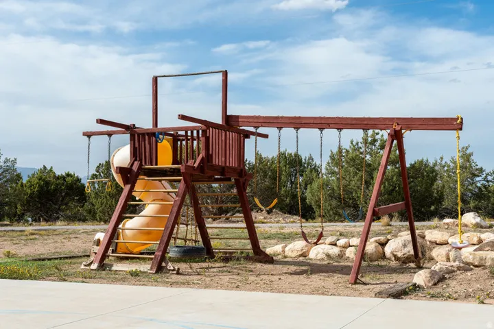 Outdoor play structure featuring a slide, swings, and rock landscaping