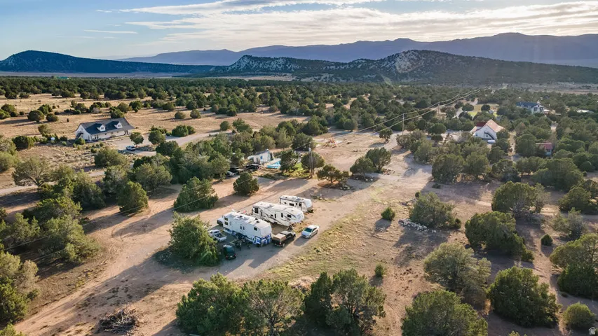 Expansive property with natural vegetation, multiple building structures, and surrounding mountainous terrain