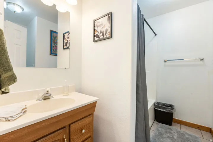Wood-finish vanity with a single basin sink and wall-mounted mirror