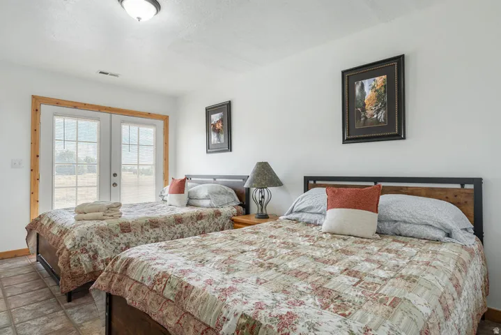 Dual French doors with natural wood trim, wood-finish flooring, and white walls
