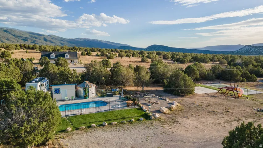 Expansive property featuring an outdoor swimming pool with a surrounding fence, a detached building, and a separate structure with a conical roof