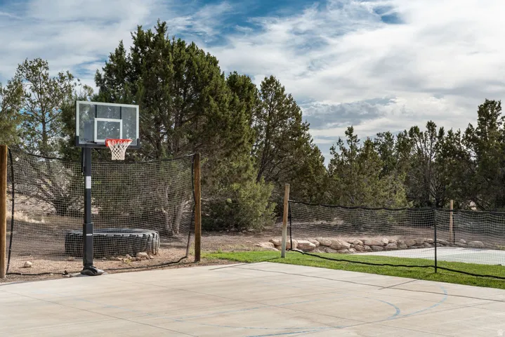 Concrete sports court with a basketball hoop and net fencing