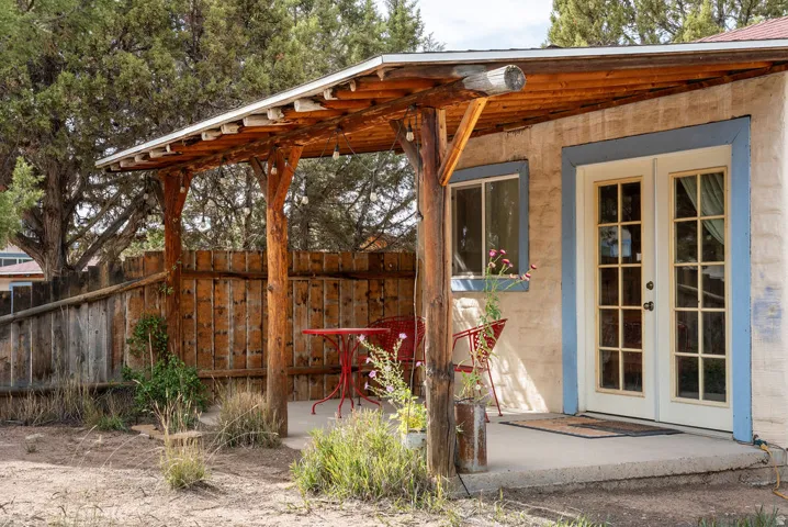 Covered outdoor patio with a concrete slab, rustic wood beam pergola, and string lighting