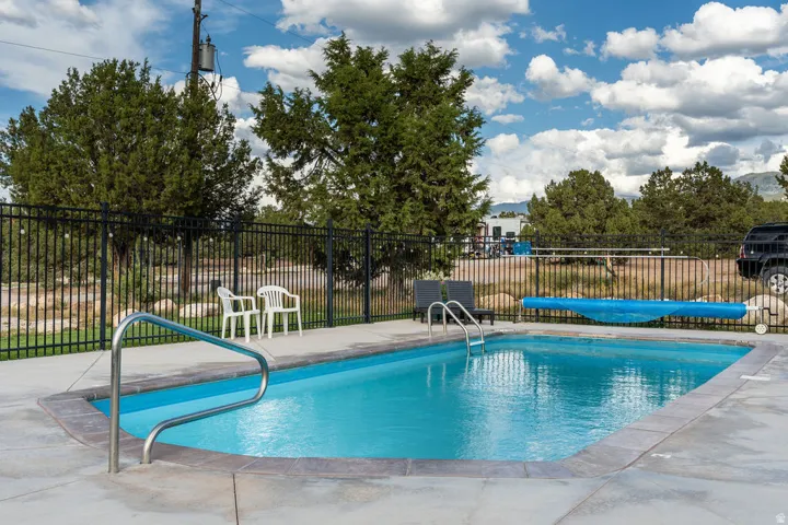 Rectangular inground swimming pool with a concrete surround and perimeter fencing