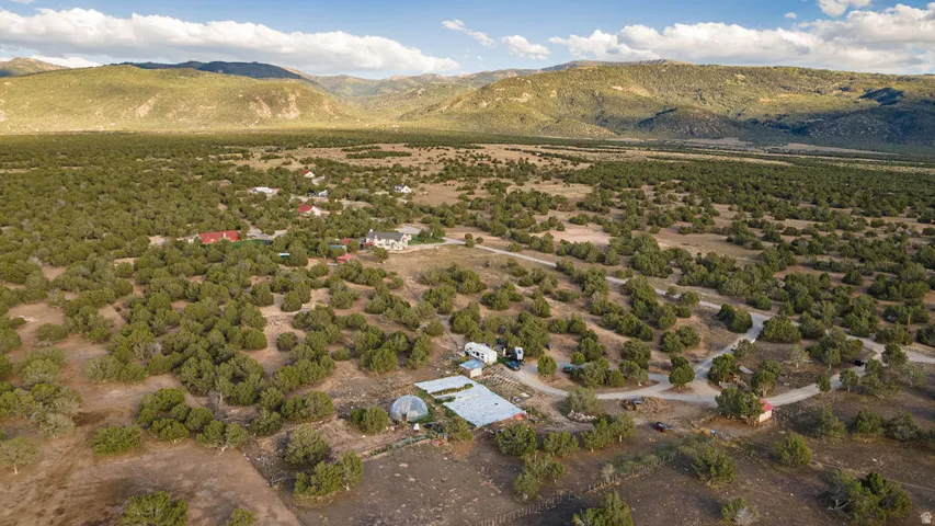 Expansive property featuring mature trees, multiple structures, and a mountain backdrop