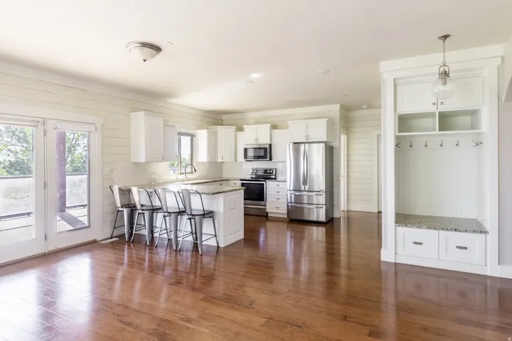 Open-concept kitchen with stainless steel appliances, white cabinetry, and a central island with bar seating