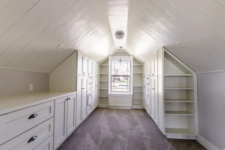 This quaint reading nook is framed with cabinets and a sloped plank ceiling with central lighting fixture
