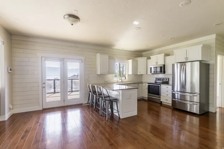 Hardwood flooring, white shaker cabinetry, stainless steel appliances, central island with seating, and glass panel French doors