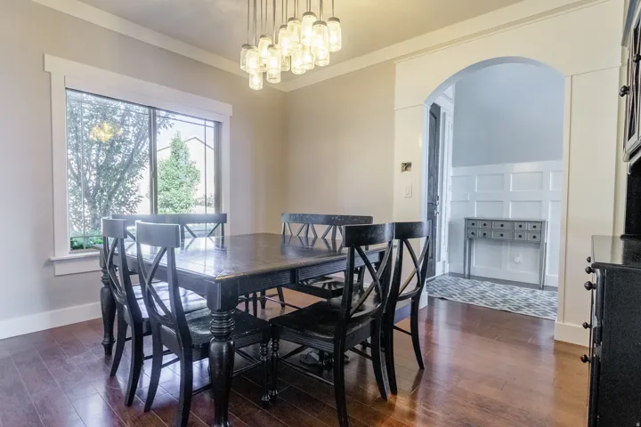 Hardwood flooring, recessed window with thick trim, elegant chandelier, arched entryway, and crown molding