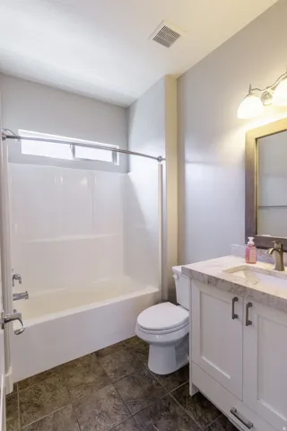 White vanity with a stone countertop, an undermount sink, and bronze-finish hardware