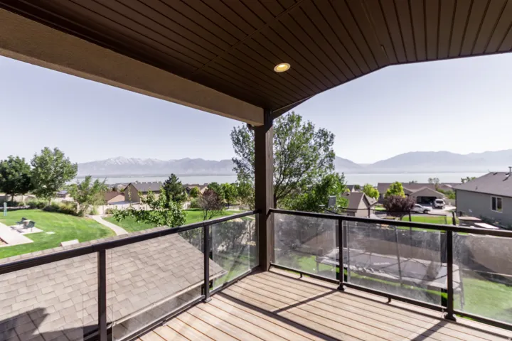 Covered balcony with wood-finish decking and glass panel railing