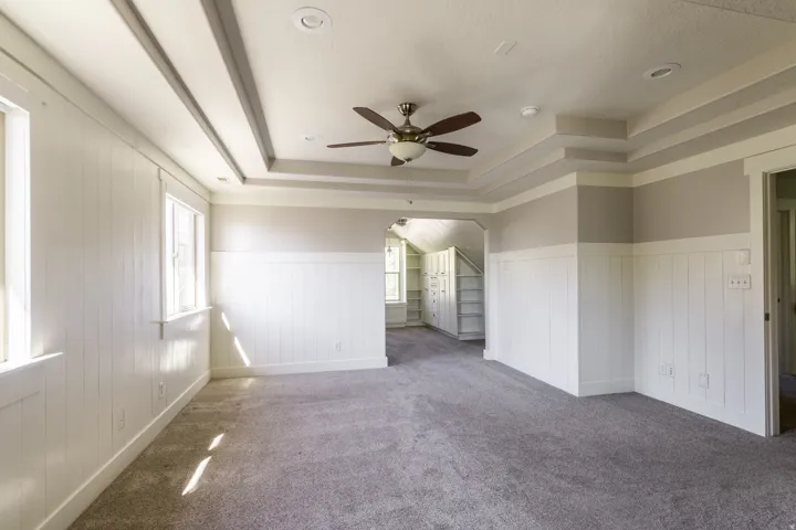 The primary suite features a tray ceiling with recessed lighting and ceiling fan, board and batten wall