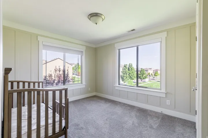Neutral-toned room featuring two windows, carpet flooring, and board and batten wall detailing
