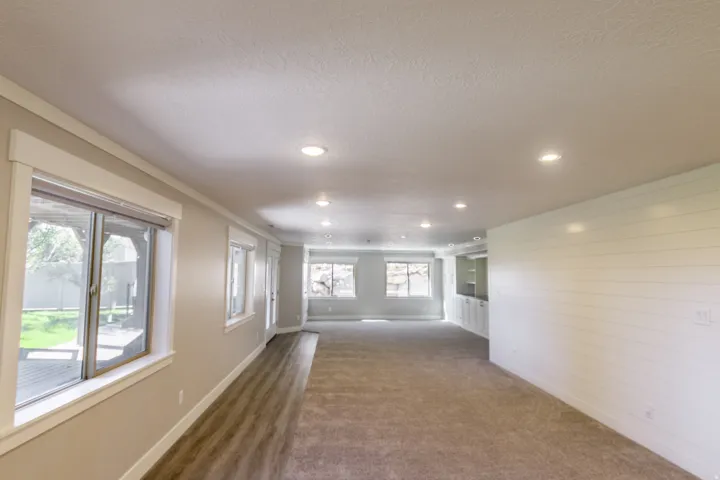 Recessed lighting illuminates this expansive space, featuring both carpeted and wood-finish flooring