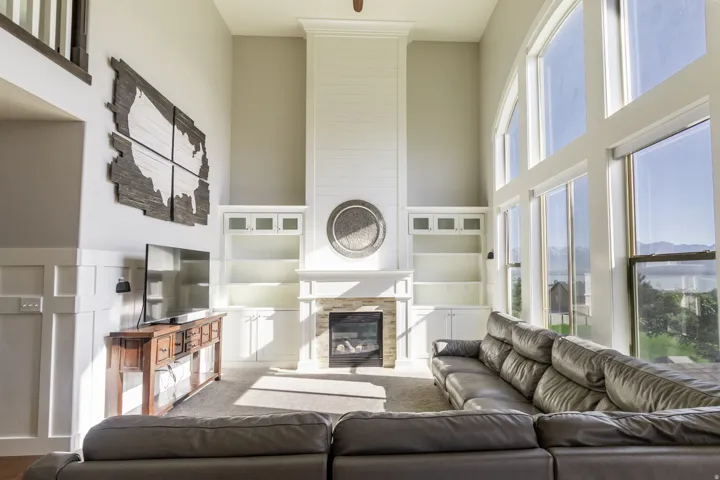 Two-story vaulted ceiling, expansive window wall, built-in shelving, stone-surround fireplace, and wainscoting