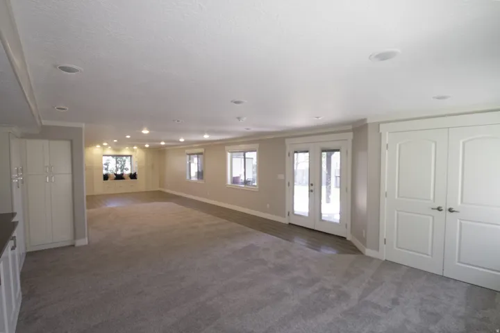 Spacious room featuring recessed lighting, multiple windows, French doors, and built-in cabinetry