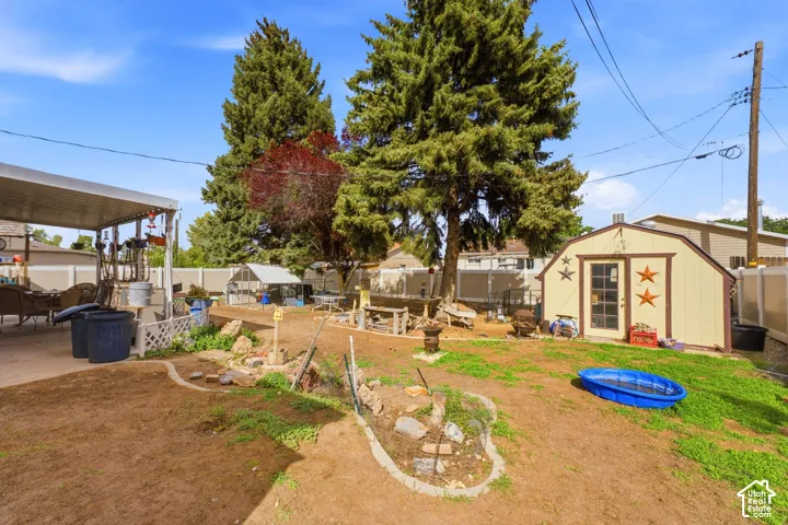 Expansive backyard featuring a covered patio, detached storage shed, and mature trees