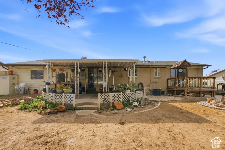 Expansive yard space featuring a covered patio, an elevated wood deck, and partial brick exterior