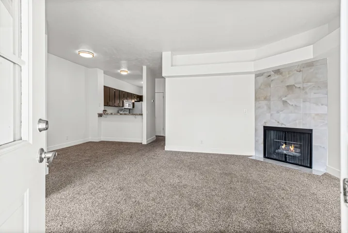 Living area featuring a tiled gas fireplace, recessed ceiling, and open layout connecting the dining area and kitchen with breakfast bar.