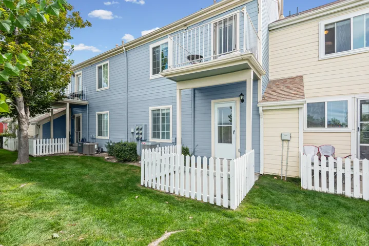 Rear exterior featuring a ground-level patio and a white picket fence.