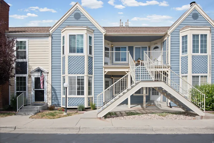 Multi-level facade with light blue and beige siding, featuring a prominent bay window