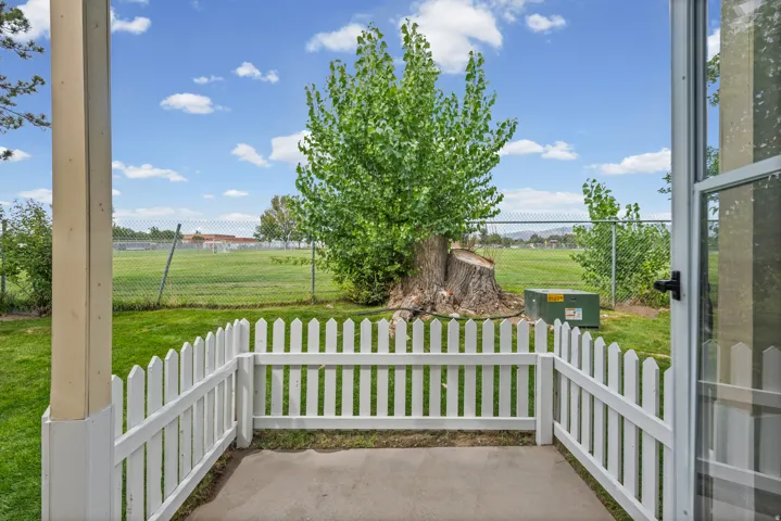 Peaceful patio area featuring a concrete surface, white picket fencing, and direct access to a grassy expanse.
