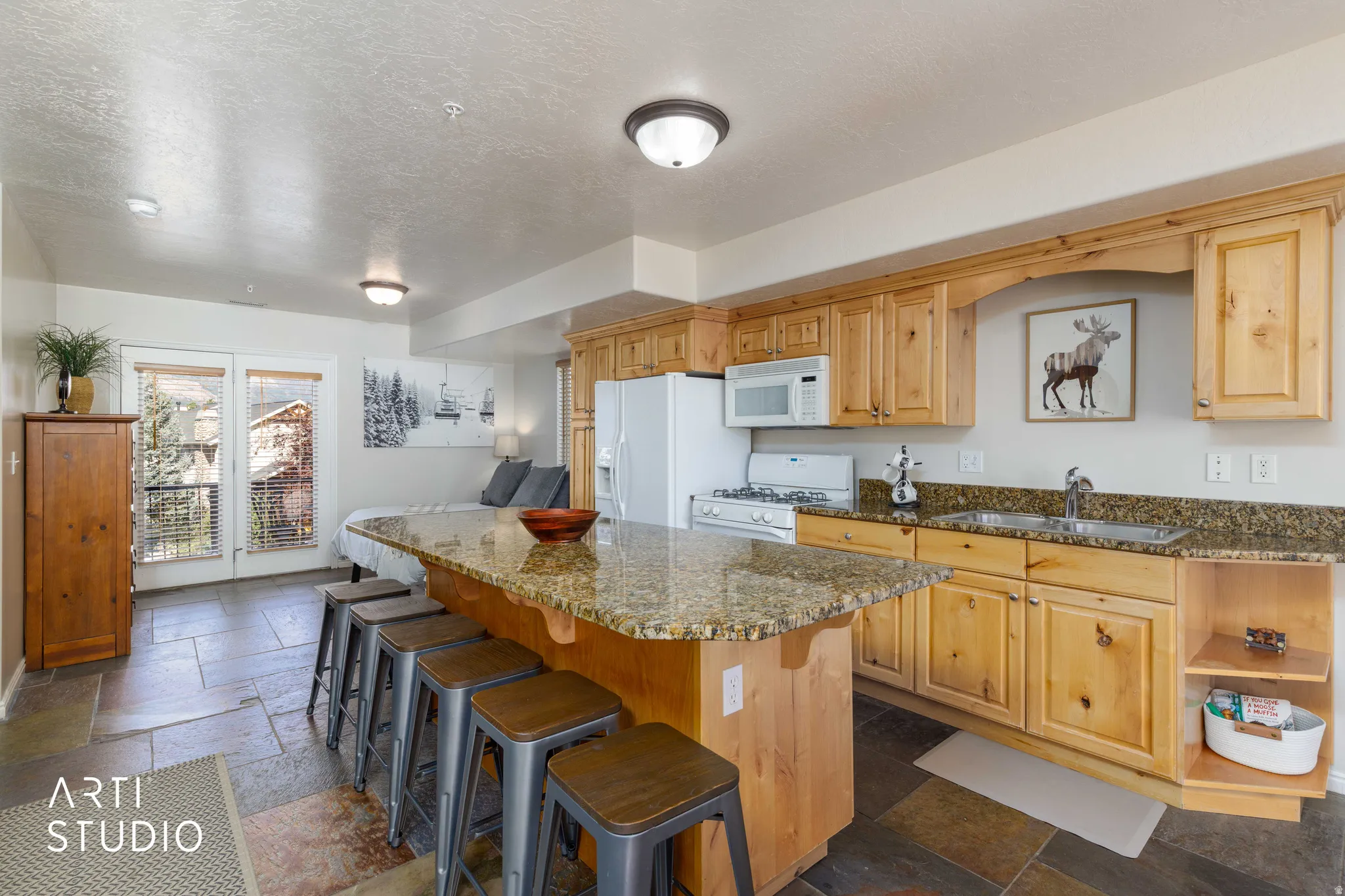 Kitchenette with wood-finish cabinetry, granite-style countertops, and a full suite of appliances