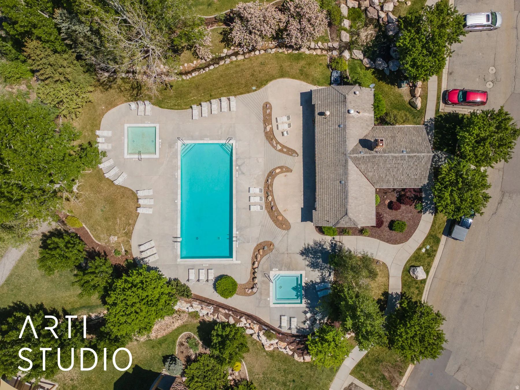 Outdoor leisure area featuring a large swimming pool, two additional square pools, a paved patio, and mature landscaping