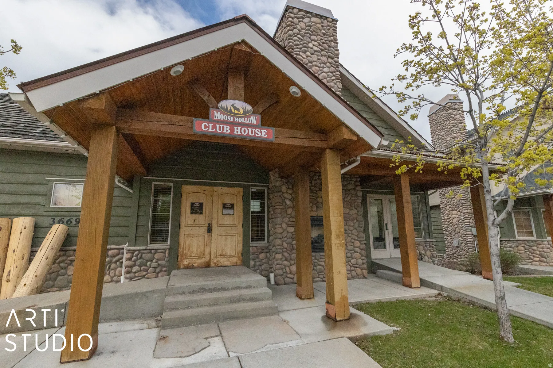 Exposed timber framing, stone veneer facade, gabled entry, wood shake roofing, and a concrete approach