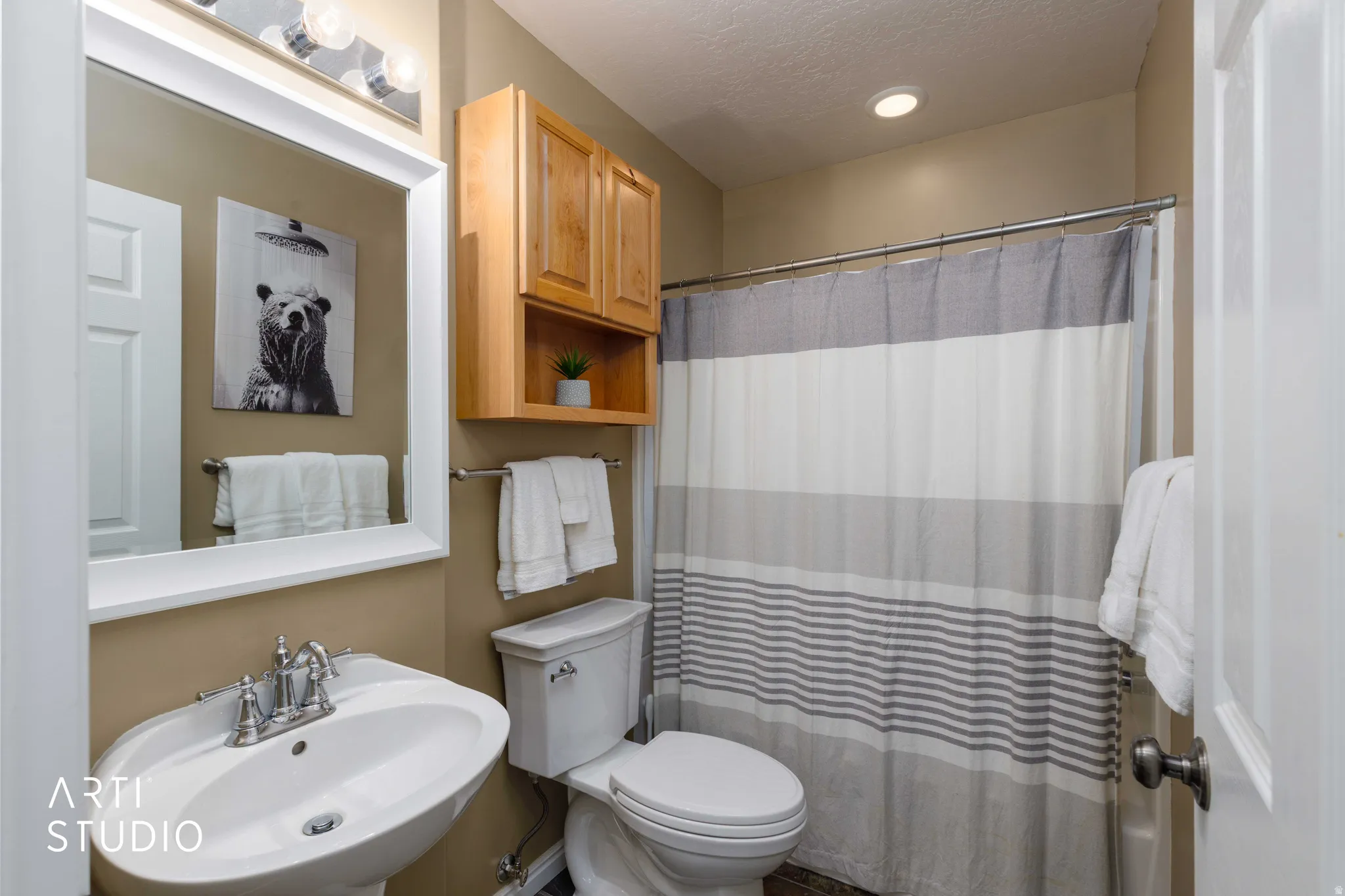 Pedestal sink with chrome faucet, framed mirror with overhead vanity lighting, wood-finish wall-mounted cabinetry, and recessed ceiling lighting