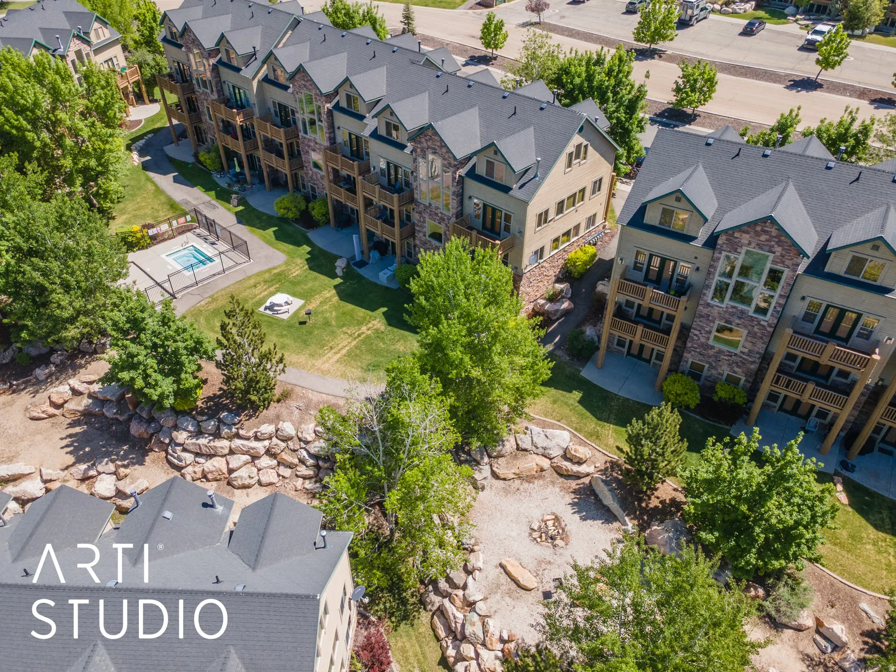 Condominium complex with multi-level balconies, stone and stucco exterior, and gable roofs