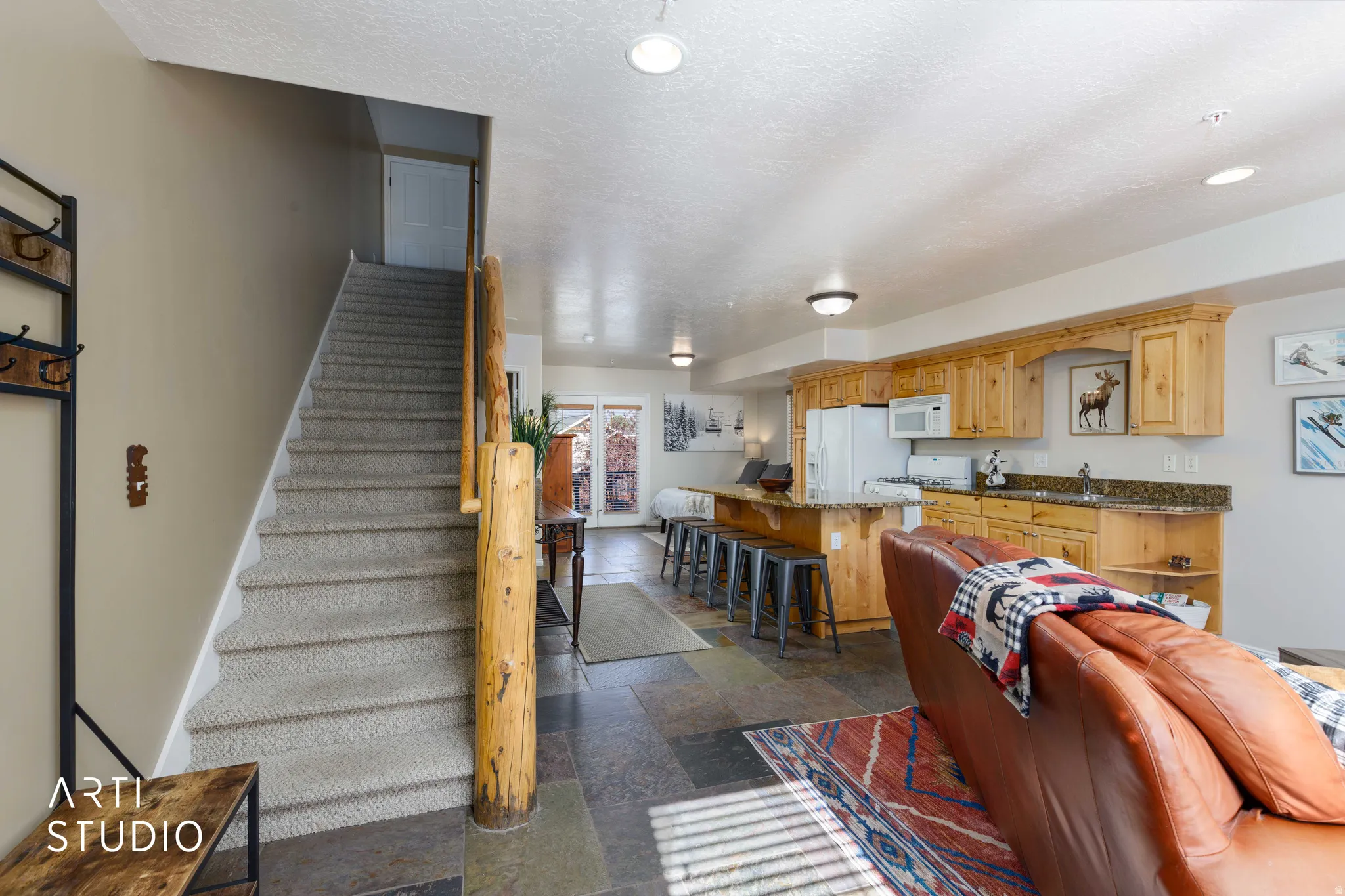 Open-concept living area featuring a walk-through kitchen with wood cabinetry, a breakfast bar, and a stone-finish countertop and sleeping areas for up to four guests