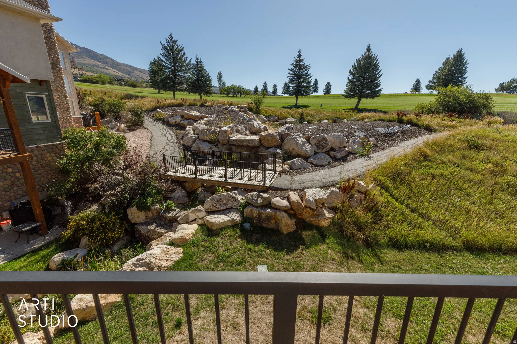View from South baclony overlooks Wolf Creek golf course. Stone exterior with a wood balcony, manicured landscaping, a decorative bridge.