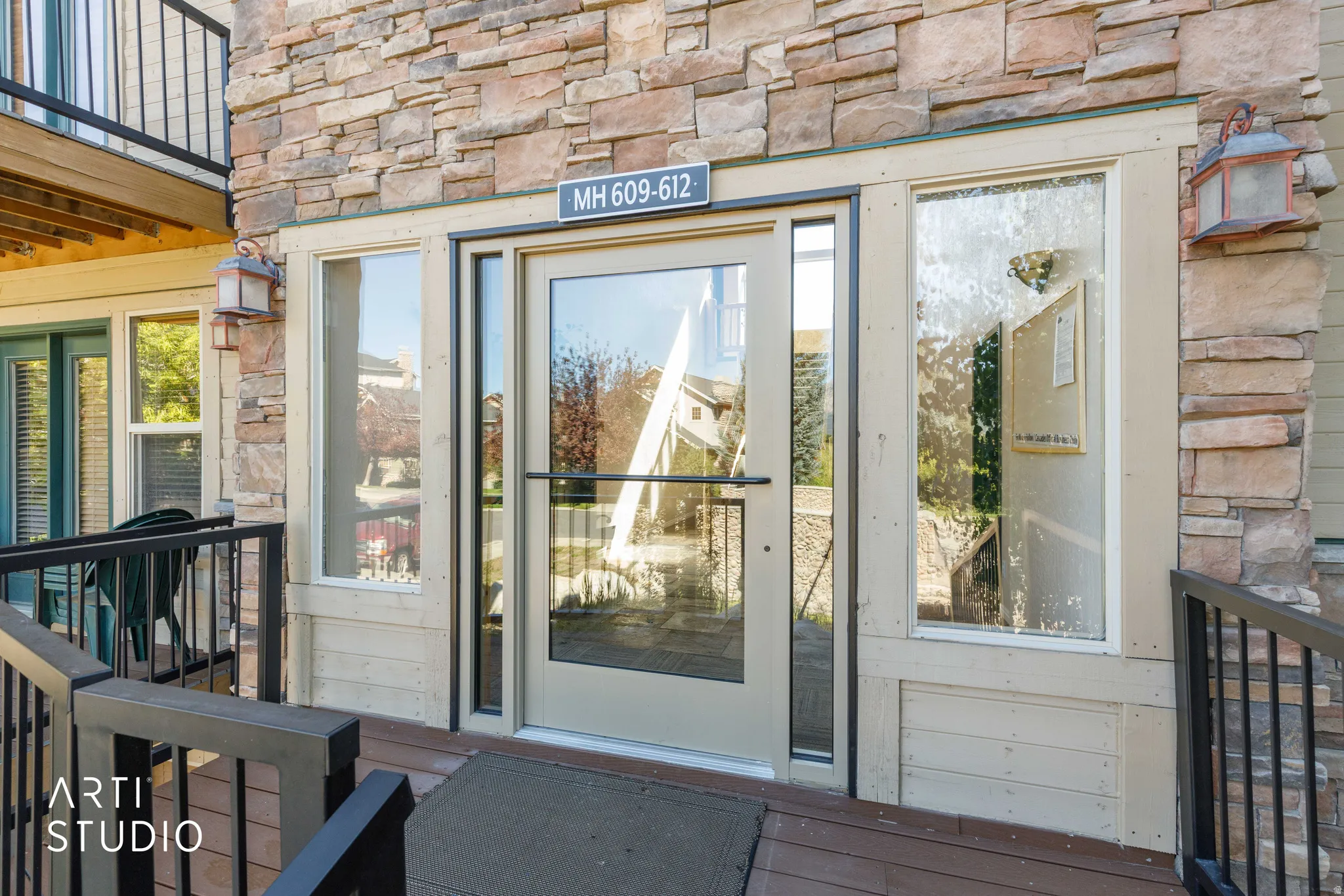 Stone veneer exterior with a glass-paneled entry door, transom, and sidelights